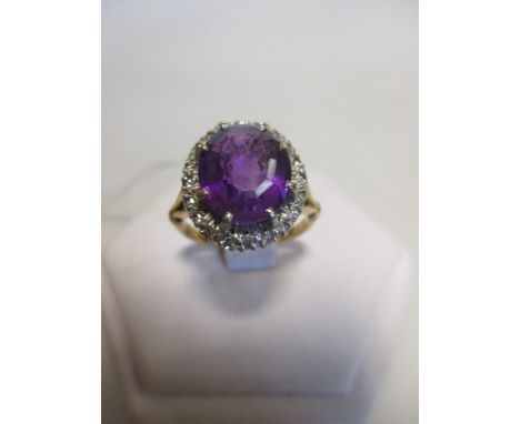 An 18ct amethyst and diamond ring, the oval amethyst, 11.2 x 9.6 x 6.2mm, claw set to a border of small round brilliant cut d
