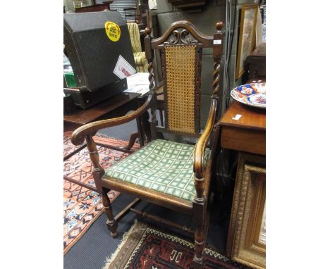 A Jacobean style open armchair with carved and caned back outswept arms, needlepoint seat and turned legs united by stretcher