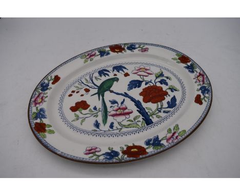 A hand painted antique Booths oval ceramic platter with central plaque depicting a green parrot in a tree with various floral