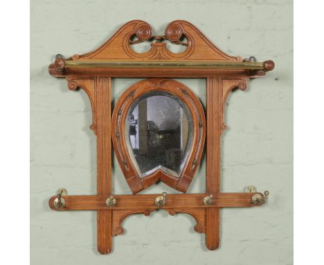 An oak framed wall hanging coat rack featuring central horseshoe bevel edged mirror and brass mounts. Approx. dimensions of f