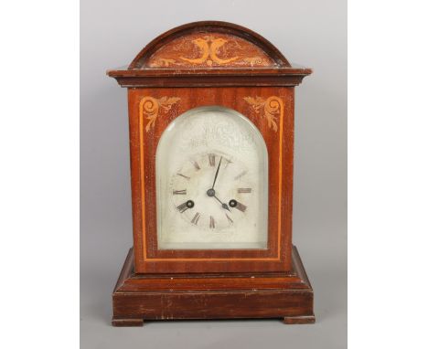 An antique German walnut bracket-shaped mantel clock by Junghans, with inlaid arched top and decorated dial. Roman numerals. 