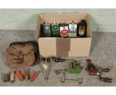 A box of shooting and ammunition reloading accessories, including empty shotgun cartridges with pouch, brass capper and decap