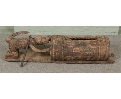 A carved African tribal slit drum modelled after the Ivorian Djidji Ayôkwé "talking drum" featuring carved animal support, po