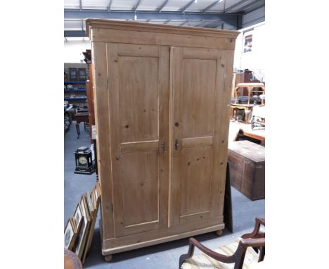 A 19th Century French stripped pine armoire, plain cornice, double panel doors and peg feet, 207 by 130 by 53cm.
