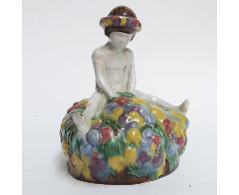 A Weiner Werksatte style ceramic figure of a child sitting on a floral tuffet, in the style of Michael Polony and Josef Hoffm