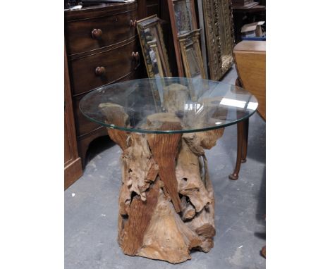 A contemporary glass-topped side table, with carved wooden base simulating a tree trunk.