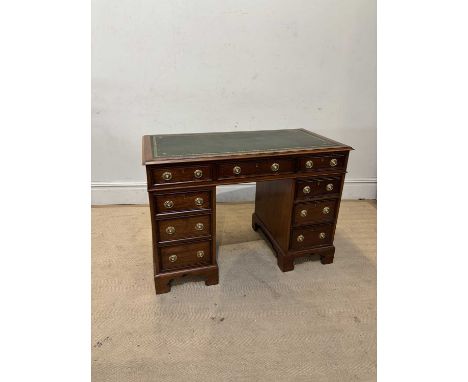 An early 20th century mahogany kneehole twin pedestal desk with green leather inset top above an arrangement of seven drawers