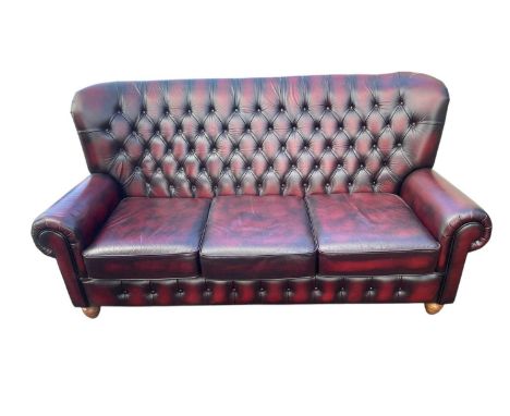 A modern maroon leather Chesterfield type wingback three seater sofa, length approx 180cm.