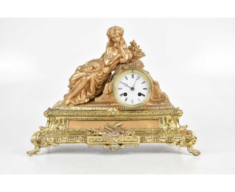 A late 19th/early 20th century French figural mantel clock representing a maiden beside book leaning on the drum shaped ename