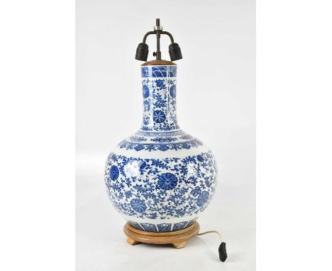 A large Chinese blue and white table lamp, decorated with lotus flowers and auspicious symbols, on turned wooden base, height