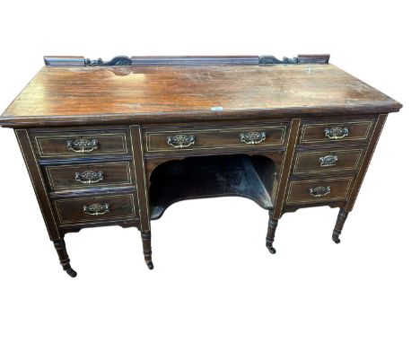 An Edwardian inlaid mahogany kneehole dressing table, with carved raised back above an arrangement of four drawers and undert