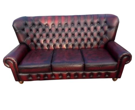 A modern maroon leather Chesterfield type wingback three seater sofa, length approx 180cm.