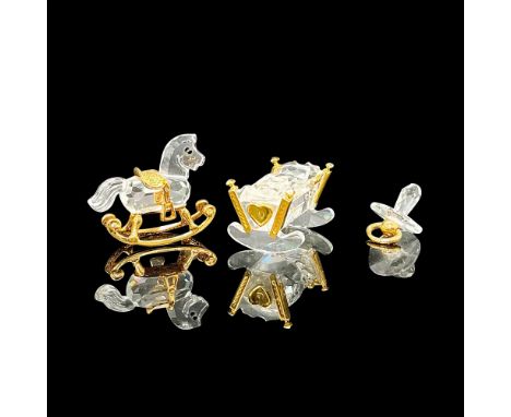 A collection of miniature figures of a rocking horse, a cradle, and a pacifier. Clear crystals with gold plated. Swarovski ma