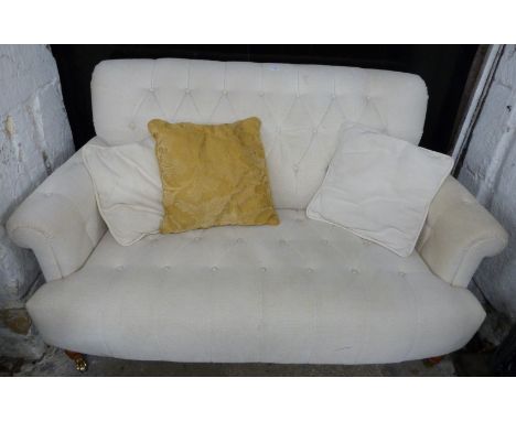 Laura Ashley cream button back two seat sofa raised on turned legs and brass castors, W146cm