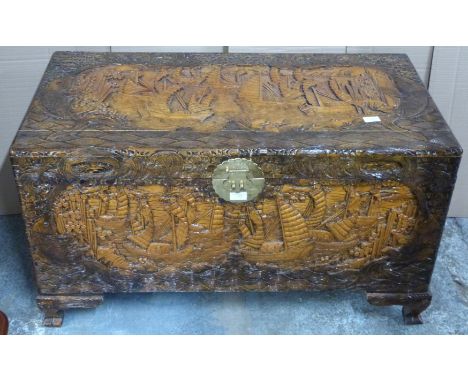 Chinese heavily carved camphor wood trunk with engraved brass lock raised on carved bracket feet, W100 x D54 x H56cm