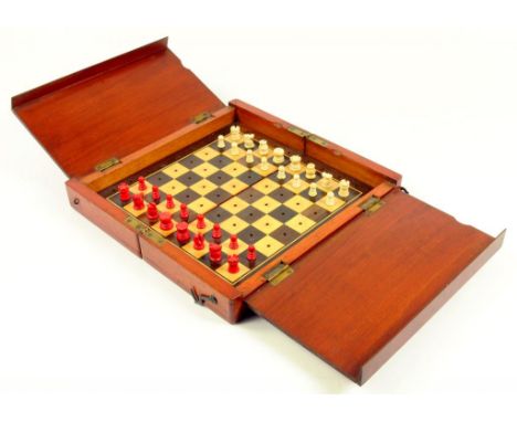 A VICTORIAN MAHOGANY TRAVELLING CHESS BOARD CONTAINING A SET OF CONTEMPORARY MINIATURE BONE CHESS MEN, STAINED RED AND NATURA