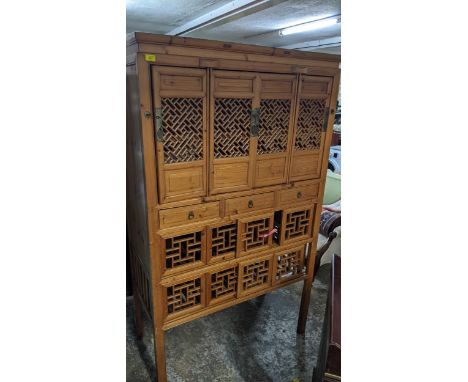 A 20th century Chinese light wood side cabinet having two rows of four sliding doors with pierced decoration, on square legs,