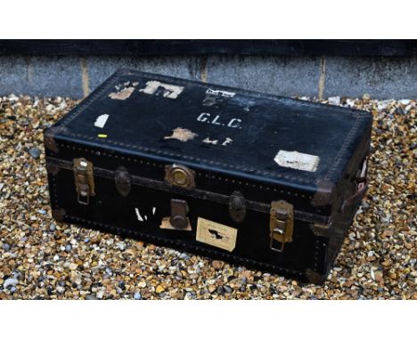 A vintage navy blue steamer/school trunk stenciled ownership, initials 'G.L.C' and remnants of paper travel labels, floral fa