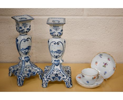 A pair of Delft blue and white candlesticks 24 cm high to/w a Meissen coffee cup and two saucers, painted with Deutsche blume
