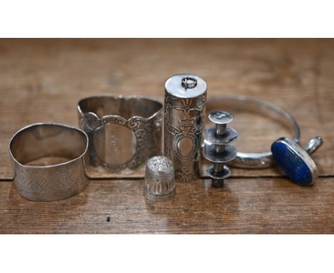 A .925 standard cotton spool in embossed cylindrical case, two silver napkin rings, an engraved hinged bangle and a thimble (