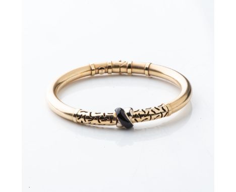 A GOLD CROSS BANGLE  Enamel, cross-over to the center, with African hand pierced design to the top, in 14ct yellow gold, tubu