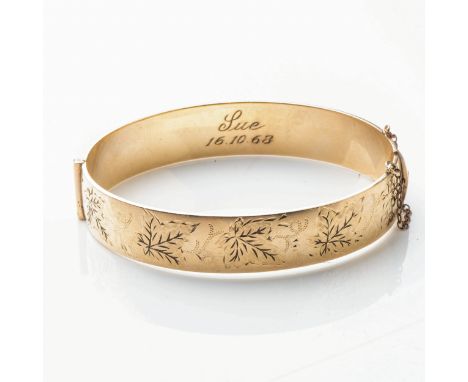 A GOLD PLATED METAL CORE BANGLE  Hinged, 12mm wide, with floral engraving 