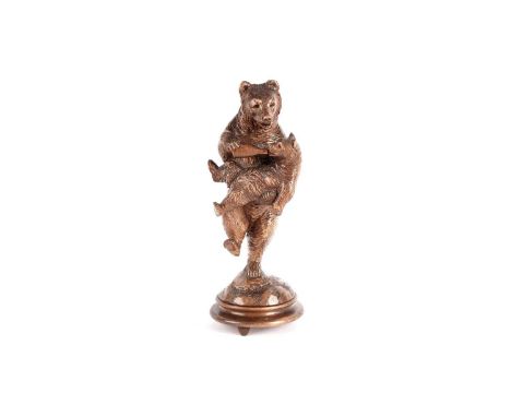 An early 20th Century Black Forest carved wood figure group of a bear and cub, modelled feeding, raised on a footed circular 