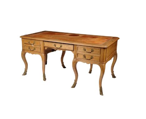 A large French light oak writing desk, with moulded edge enclosing a tooled writing area, the central knee hole flanked by tw