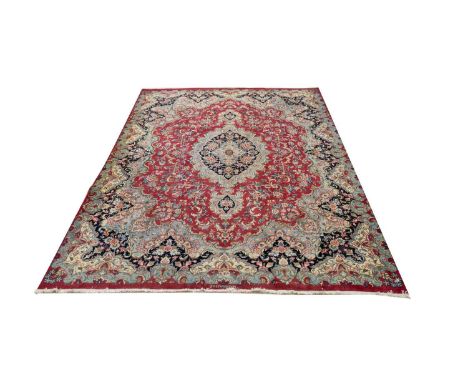 A Kirman carpet, the floral medallion and scrolls on red ground, 387 x 296cms.