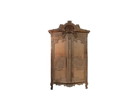 A large and impressive French provincial style carved light oak armoire, the cornice profusely carved with acanthus above whe