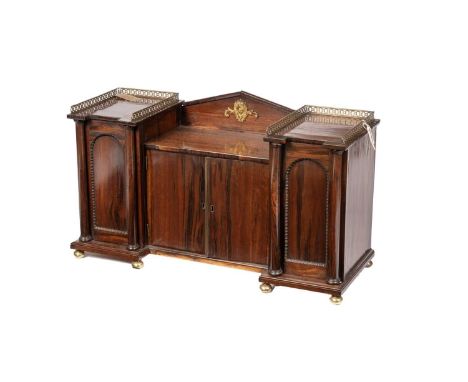 A Regency rosewood cabinet, of drop centre architectural form, the central raised pediment with brass putti embellishments fl