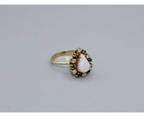 An opal, diamond and emerald dress ring. Stamped 585 to the outside of the shank. Size N. Approximate weight 3.6 grams.