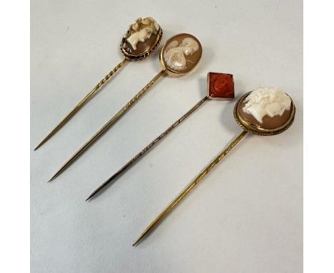 A coral cameo stick pin, in the form of an outwards facing woman, along with three shell cameo stick pins, featuring high rel