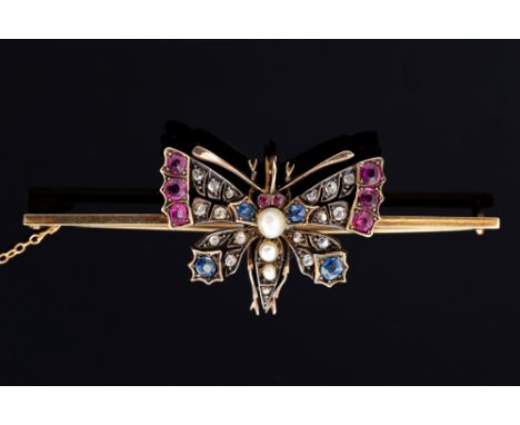 An Edwardian diamond, sapphire ruby and pearl set butterfly on bar brooch, silver settings, the butterfly applied to a yellow