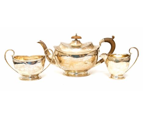 A George V silver plain oval shaped three piece tea service comprising teapot, milk jug and sugar bowl, the teapot with fruit