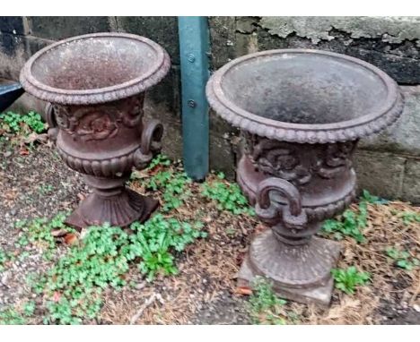 A pair of late Victorian cast iron two handled pedestal urns