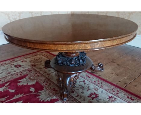 An early Victorian oak tilt top pedestal breakfast table, the circular top raised on an elaborately carved base, standing on 