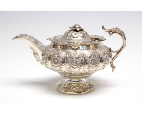 A George IV melon shaped batchelor's silver teapot, the lobed body and curved spout chased with floral sections beneath a cas