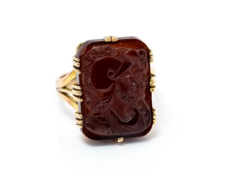 A gold and garnet cameo ring, carved with classical Roman figures, the cameo approx. 13mm x 19mm, claw set, ring size P, tota