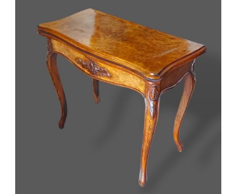 A Victorian walnut card table, the hinged top above a shaped carved frieze, raised upon cabriole legs with scroll feet 