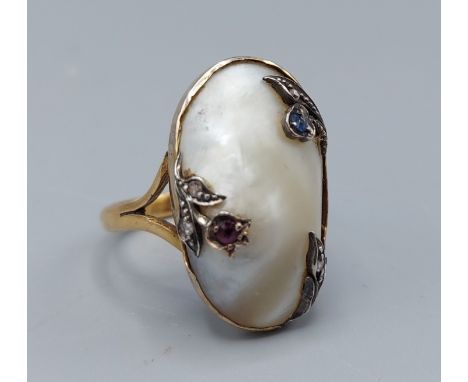 A 22ct gold Art Nouveau style ring set with mother of pearl and decorated with Ruby, Sapphire and Diamonds, ring size Q, 7.8g