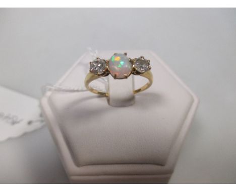 A three stone opal and diamond ring, the central opal cabochon flanked by an old brilliant cut diamond to either side, all cl