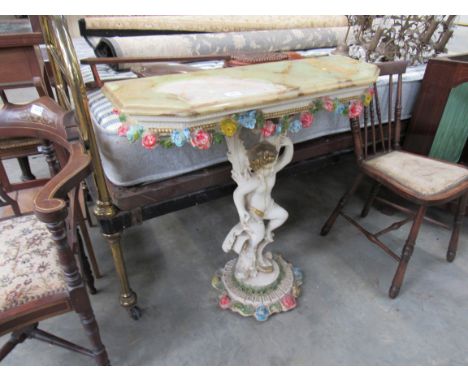 A canted corner marble top console table on painted ornate putti base 