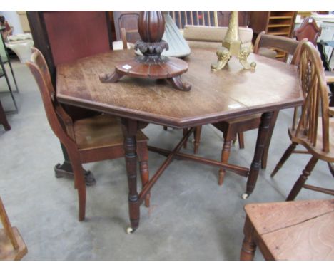 An Arts &amp; Crafts walnut octagonal top centre table on turned legs and white ceramic castors 