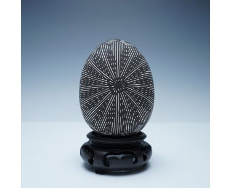 A finely crafted black and white ceramic seed pot featuring an intricate etched radial design. The delicate pattern radiates 