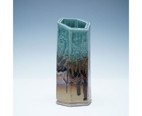 A striking signed studio pottery vase featuring a unique hexagonal form with an asymmetrical rim. The vase exhibits a captiva