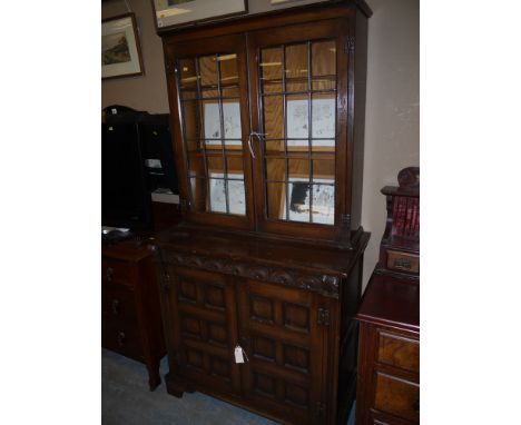 A mid 20th Century carved and stained oak bookcase, the top with two leaded glass panelled doors enclosing shelves, the botto