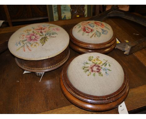 A pair of Victorian circular mahogany footstools with tapestry upholstery; and another similar stool, with hinged cover openi