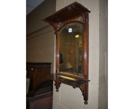 A part bevelled wall mirror, fitted shelf above and below with decorative shaped brackets and turned finials.