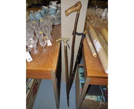 An ebony walking stick; a rustic walking stick with carved horses head handle; and another walking stick.